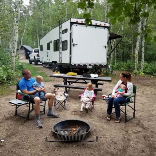 family camping in front of a trailer