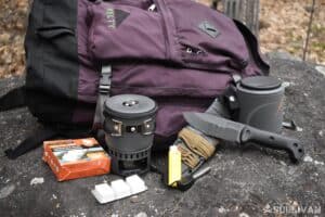 knife portable stove and fire starter next to backpack