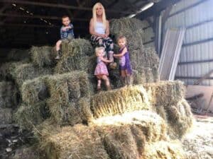 woman and kids on top of some bales of hay
