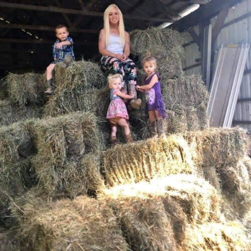 woman and kids on top of some bales of hay