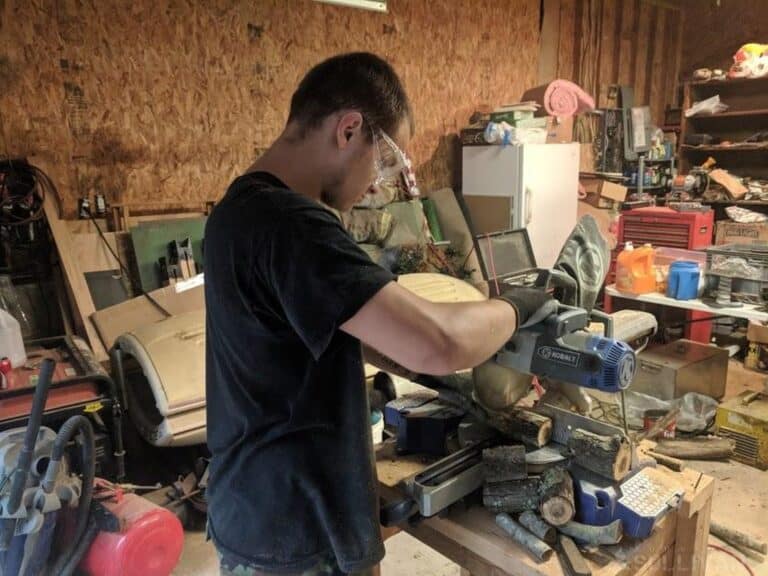 man cutting some wood branches with a circular saw