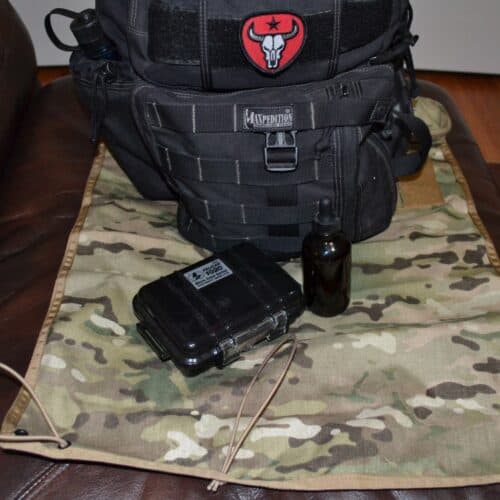 backpack and Pelican case on a small camo tarp