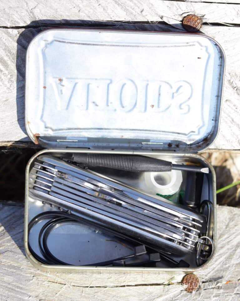 EDC kit inside an Altoids tin with multitool zip ties, carabiner, and more