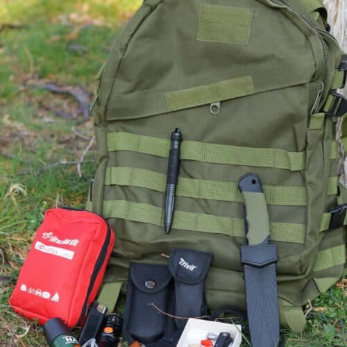 green molle bug out bag with first aid kit, knife, multi-tool, and fishing kit, next to it