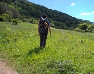 man hiking with backpack into the woods