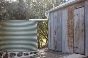 large water tank connected to and collecting water from shed roof