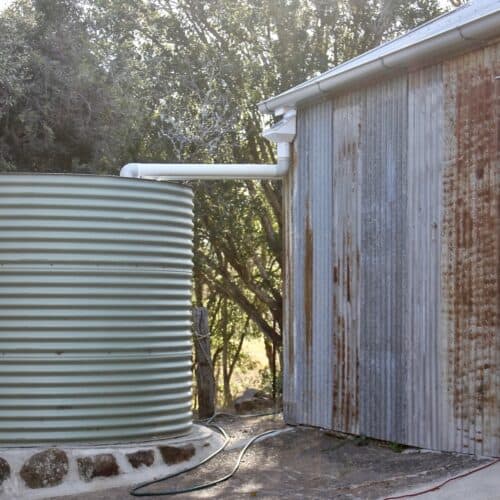 large water tank connected to and collecting water from shed roof