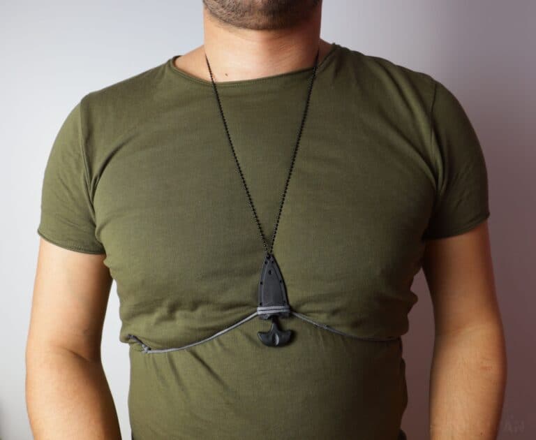 neck knife hidden underneath a t-shirt with just the metal necklace showing