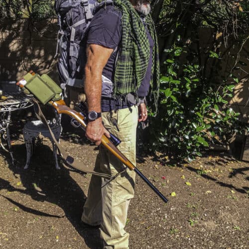 man ready to hunt with his backpack, rifle, bandana and hat