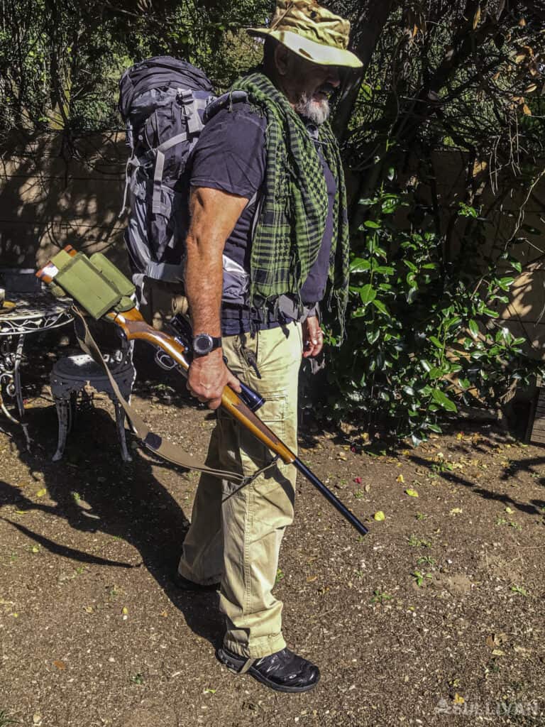man ready to hunt with his backpack, rifle, bandana and hat