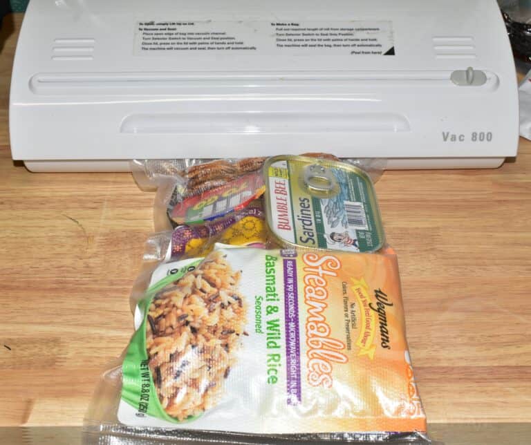 instant rice, Clif bar, crackers, and tuna sealed in zipper bag next to a vac 800 packing machine.