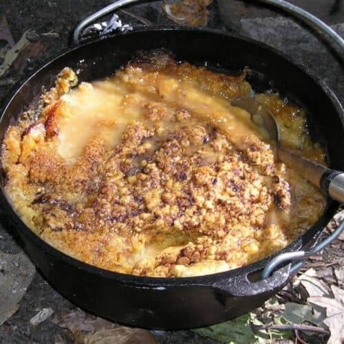 peach cobbler cooking in cast iron Dutch oven over outdoor fire
