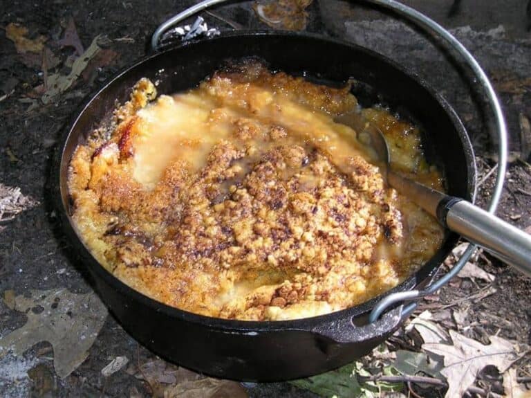 peach cobbler cooking in cast iron Dutch oven over outdoor fire