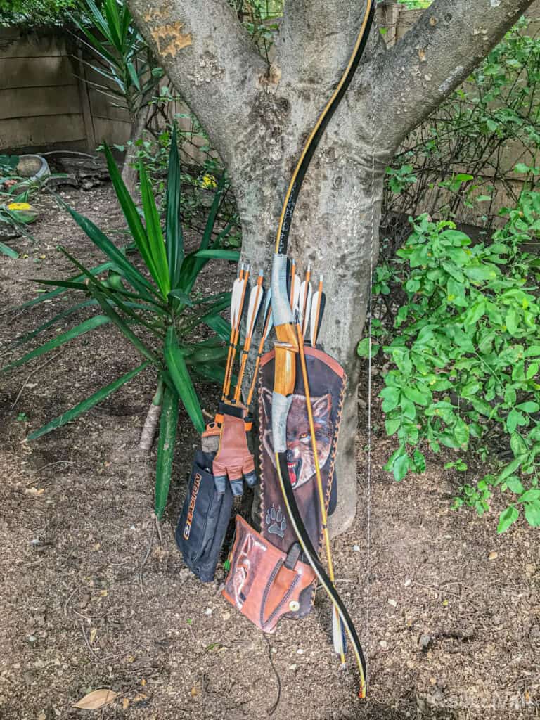 recurve bow with arrows and quiver next to tree