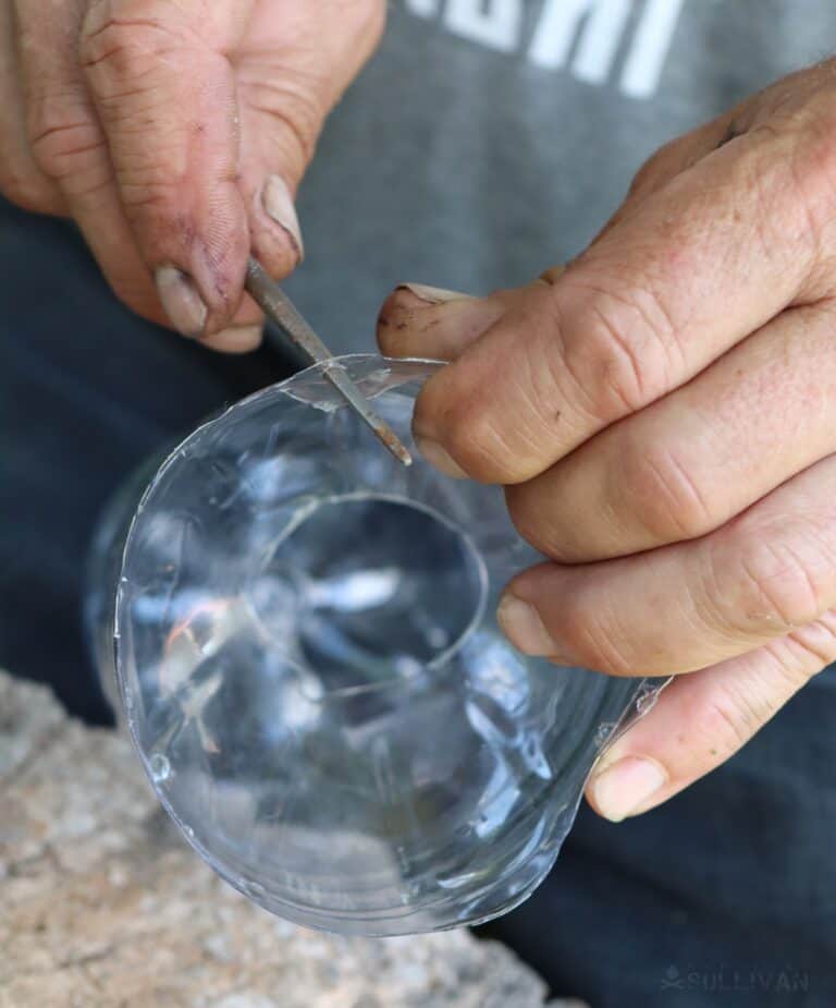 punching holes in plastic bottle with metal rod