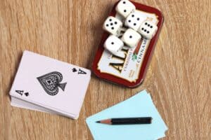 deck of cards, dice, pencil, and paper next to Altoids tin
