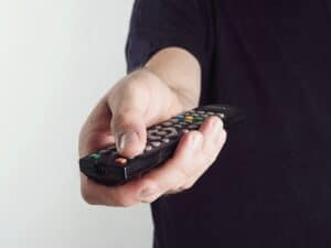 man pressing a tv remote button