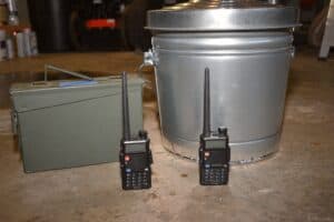 two Baofeng ham radios next to two Faraday cages