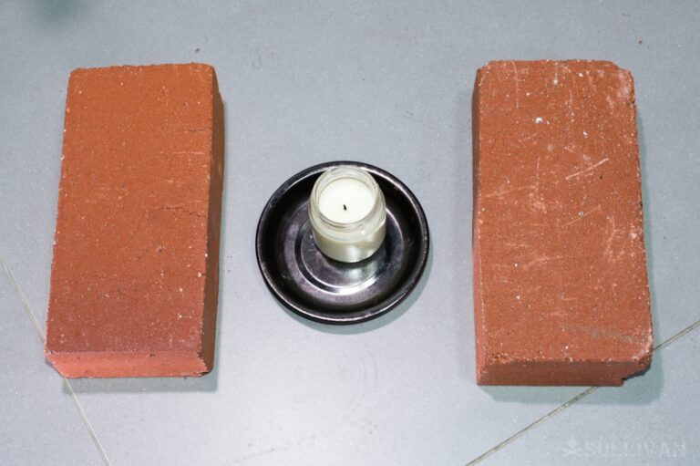 candle on metal plate with two bricks side by side