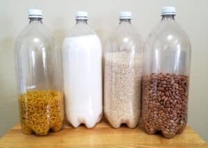 four 2-liter plastic bottles with noodles salt, rice, and pinto beans