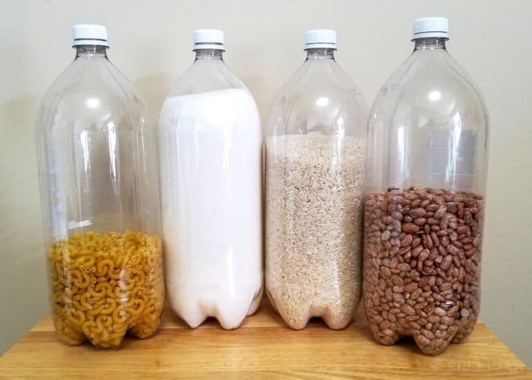 four 2-liter plastic bottles with noodles salt, rice, and beans