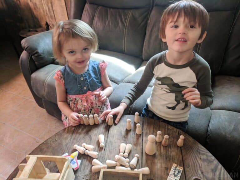 two kids playing with wood peg people