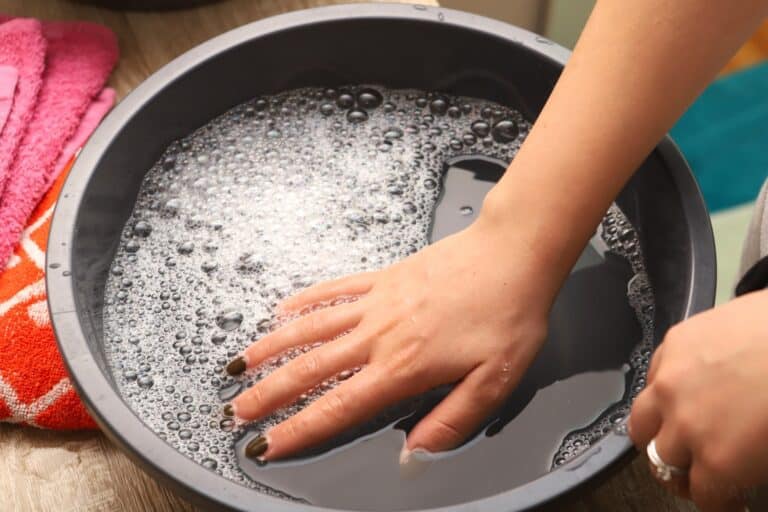hand inside wash basin with soapy water