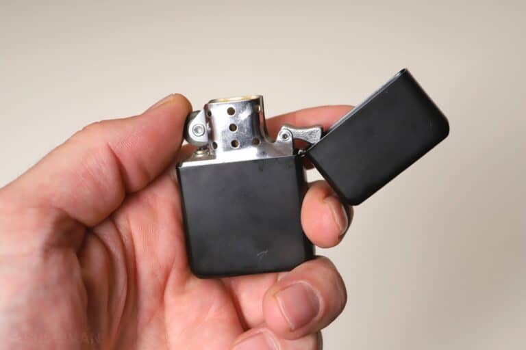 holding a Zippo lighter in hand
