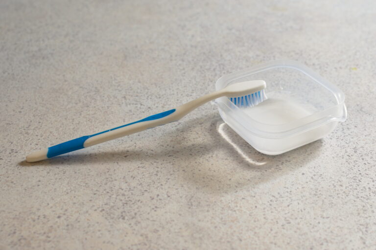 toothbrush next to container of baking soda mixed with water