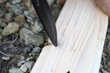 poking wooden board with knife