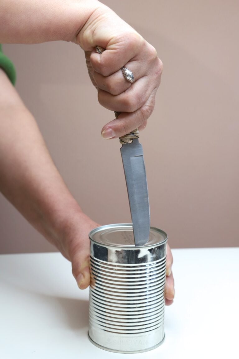 knife tip on edge of can